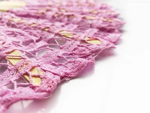 Close-up of pink lace fabric texture and bamboo ribs on an elegant folding hand fan