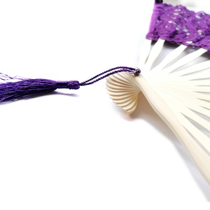 Close-up of bamboo ribs and purple lace surface with a matching decorative silk tassel