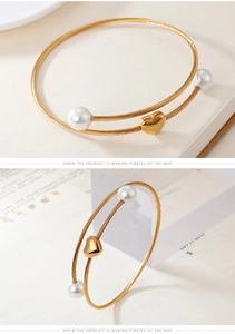 Detail of gold double-layer twist bangle with white pearls and heart charm pendant