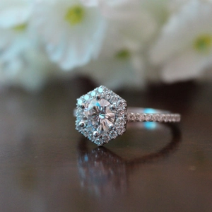 Macro shot of hexagonal halo engagement ring with round center stone and pave band