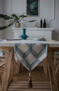 Detail of geometric pattern jacquard table runner with decorative blue tassel and bead