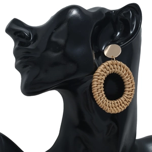 Détail macro de boucles d'oreilles créoles tressées en rotin brun sur un mannequin noir