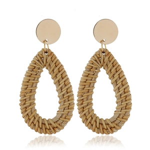 Boucles d'oreilles ethniques en rotin tressé goutte avec clous dorés sur blanc