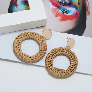 Détail macro de boucles d'oreilles géométriques en rotin tressé à la main avec clous dorés