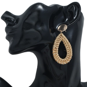 Détail de boucle d'oreille en rotin tressé à la main en forme de goutte et clou doré