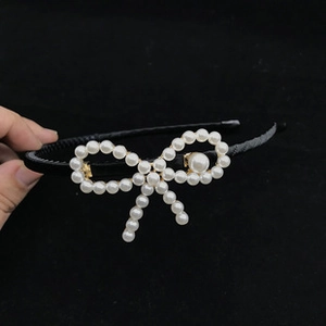 Detailed view of handmade pearl bow headband featuring white beads and a black thin base
