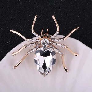 Detailed close-up of a golden spider brooch with pear-shaped crystal and rhinestone inlay