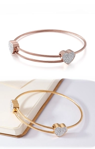 Detail of heart-shaped steel cable bracelet with sparkling pavé crystals in gold tones
