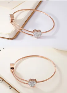 Detail of rose gold double cable bangle with sparkling heart charms and crystal inlay
