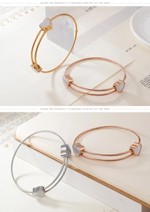 Detailed close-up of heart charm steel cable bangles in gold, rose gold, and silver finishes