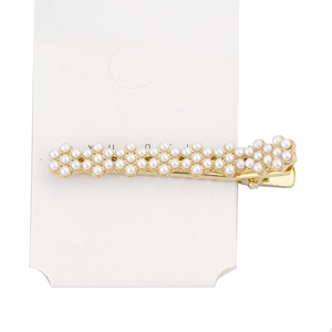 Detail of wavy gold-tone hair clip with faux pearl embellishments on display card