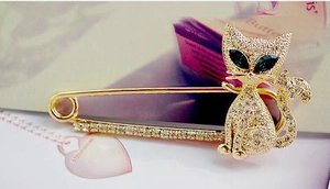 Close-up of golden cat brooch with green crystal eyes and shimmering rhinestones