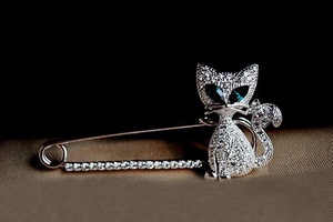 Macro shot of silver-plated cat brooch with clear zircons and blue gemstone eyes