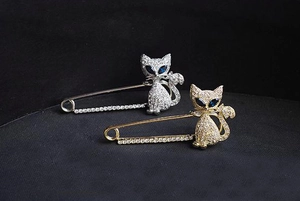 Close-up of gold and silver cat brooches with blue crystal eyes and clear rhinestones
