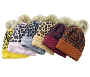 Detailed view of leopard print knit hats with faux fur pom-poms in multiple vibrant colors
