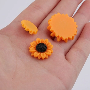 Close-up of resin sunflower charms on hand showing front and back detail for DIY hair accessories