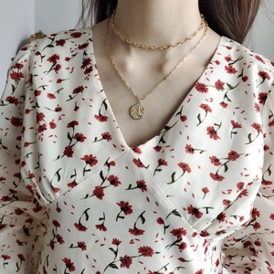 Detail of layered gold coin necklaces paired with a vintage French floral dress