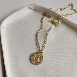 Detailed close-up of a vintage mermaid coin pendant on a stylish gold paperclip chain