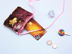 Detail of red and gold sequin coin purse with ribbon strap showing bank card capacity