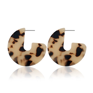Detailed view of tortoiseshell C-shape acrylic earrings with metal studs on white background