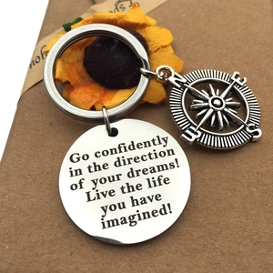 Macro of stainless steel keychain with compass charm and engraved graduation quote