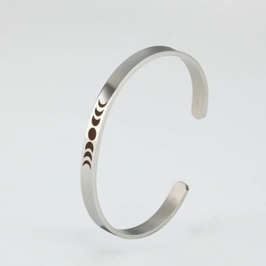 Close-up of silver stainless steel C-shaped cuff bracelet with moon phase engraving