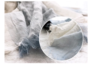 Detailed close-up of blue and white gradient cotton linen scarf with tassel texture