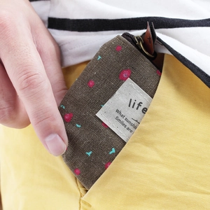 Mini canvas coin purse with polka dot pattern being tucked into a yellow pocket
