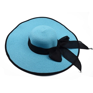 Detail of blue straw sun hat showing woven texture and elegant black ribbon bow