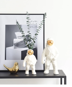 Detalle del jarrón astronauta de cerámica blanca con visera dorada y hojas de eucalipto