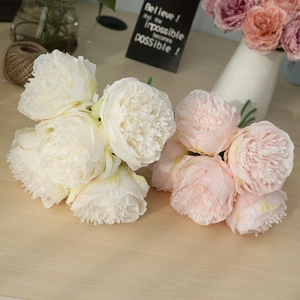 Detailed view of artificial peony silk flowers in white and pink on a wooden table