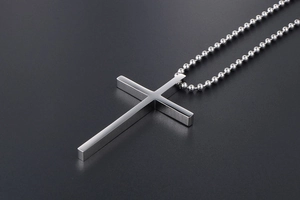 Close-up of a sleek silver titanium steel cross pendant on a classic ball chain