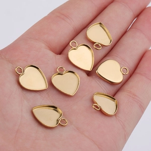 Macro shot of 13mm heart-shaped gold-plated stainless steel pendant trays held in palm