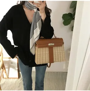 Detail of a handmade straw woven picnic handbag with brown leather trim and metal clasp