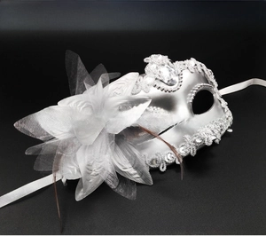 Close-up of silver masquerade mask with lace trim, crystal accents, and feather flower detail
