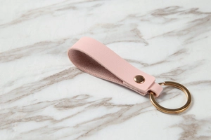 Close-up of pink litchi grain leather loop keychain with elegant gold metal ring