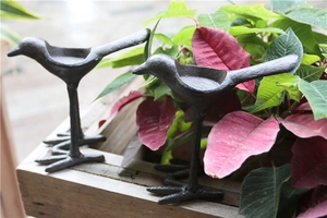 Détail de bougeoirs oiseaux en fonte vintage sur plateau bois avec décor festif