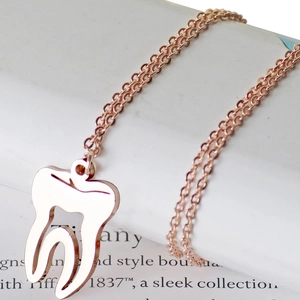 Collier en acier inoxydable or rose avec pendentif dent au design ajouré minimaliste