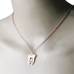 Collier avec pendentif molaire en or rose présenté sur un mannequin avec chaîne fine