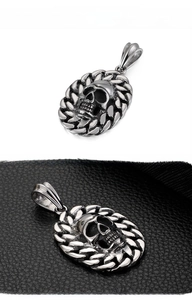 Detailed view of gothic skull pendant with chain border on black leather background