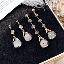 Detail of long and short gold tassel earrings with white pearls on a black background