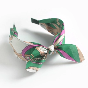 Close-up of fabric headband with colorful vintage pattern and bow detail on white base