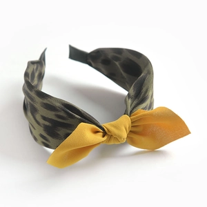 Detail of fabric headband with dark green leopard print and a bright yellow bow accent