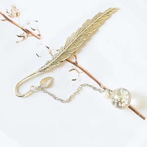 Vintage silver metal feather bookmark with dried flower pendant on white background