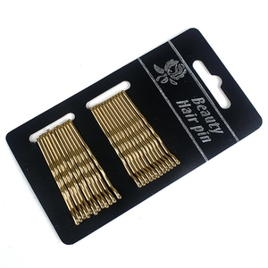 Golden wavy metal hair pins on black cardboard packaging shown from a top-down angle