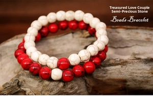 Detail of red and white semi-precious stone beaded bracelets on natural wood background