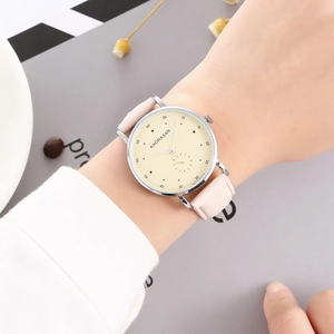 Women's quartz watch with pink leather strap and silver case on a minimalist desk setup
