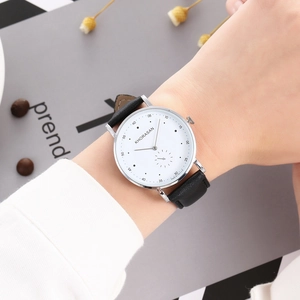 Business style quartz watch with silver case and black leather strap worn on wrist