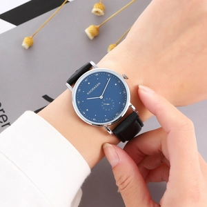 Close-up of minimalist women's business watch with navy blue dial and black leather strap