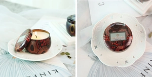 Detail of artistic floral tin candle with flickering flame and vintage lid on tray